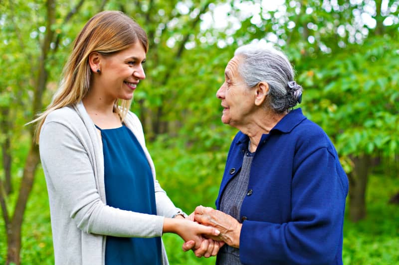 Elderly lady and carer holding hands in the garden